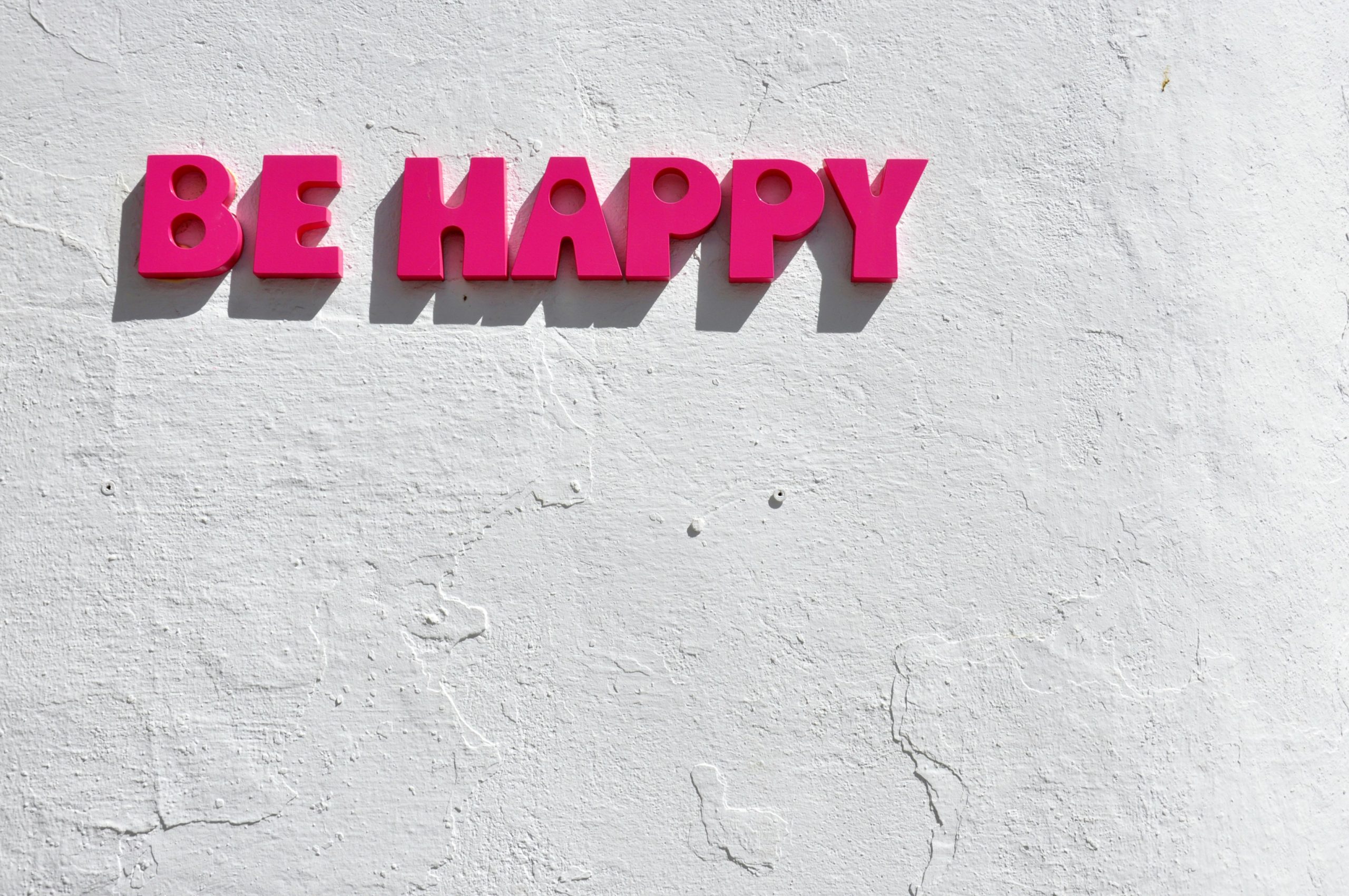 Texte Be Happy en lettres roses symbolisant le bien-être, la santé mentale positive et le développement personnel